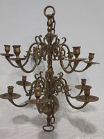 Front view of the heavy brass hanging candelabra with 12 candle holders and detailed scrollwork arms.