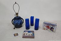Full lot showing cobalt blue Brush McCoy pottery lamp, three cobalt blue glass vases, glazed ceramic tiles, and vintage French advertising tin.