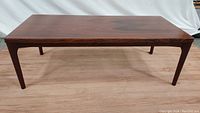 Full front view of the vintage rosewood coffee table showing rectangular top and four tapered legs.