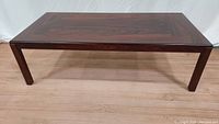 Front view of vintage rosewood coffee table showing straight legs and rectangular top.