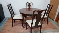 Full view of round cherrywood dining table with 4 dining chairs.