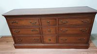 Front view of vintage Ethan Allen solid wood dresser showing all 12 drawers with metal handles and the water marked top surface.