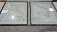 The two framed maps lying flat side by side, showing both maps' overall layout, frames, and matting.