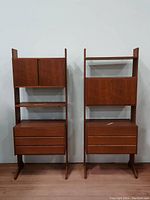 Two free-standing mid century modern teak wall unit cabinets side by side