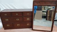 Wide view of the mahogany bachelor chest with multiple drawers and brass hardware alongside matching framed mirror.