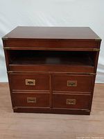 Front view of the nightstand showing four drawers and an open shelf with brass hardware and corner brass caps.