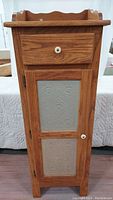 Front view of the wood pie safe cabinet showing the drawer at top and door with two punched tin panels below.