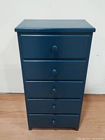 Front view of the 5-drawer colonial blue solid wood cabinet against a white wall on wooden floor, showing drawer knobs and cabinet base.