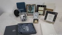 Seven picture frames displayed on white surface showing mix of crystal, silver, and metal frames, with boxes and inserts visible