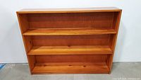 Full front view of vintage solid wood 3-shelf bookcase showing all shelves and wood grain.