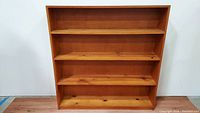 Front view of the vintage solid wood 4-shelf bookcase showing natural wood grain and even shelving.