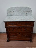 Front view of antique Victorian walnut wash stand with white marble top and backsplash, showing three drawers and metal ring handles