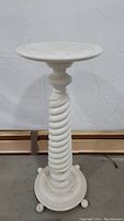 Full view of the white pedestal table showing the round top, twisted swirl pedestal, and circular base with feet.