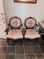 Photo of front two antique needlepoint chairs with carved wooden frames and Victorian-style upholstery showing minor fading
