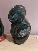 Front view showing two protruding circular figural faces carved in verdite stone.