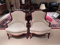 Front view of both armchairs side by side on carpet with dining table in background
