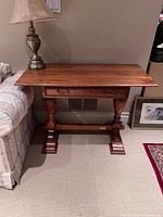 Front view of Adam Bede console table placed against wall between couch and picture frame. Lamp placed on left corner of table.