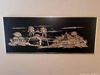 Front view of the bamboo art piece showing the tropical scene with house and palm trees on black background with frame