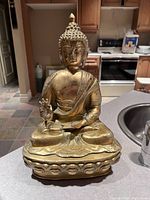 Front view of seated brass Buddha statue on lotus base