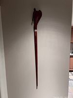 Full length view of the carved wood walking stick showing the tapering wooden shaft and horse head handle.