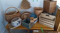 Various wicker and woven baskets arranged on wooden table with natural fiber fan and wooden planter box