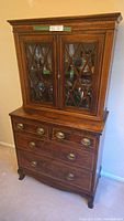 Front view of antique wooden hutch with glass lattice doors and four drawers