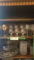 Shelf view showing multiple types of bar glasses and glass bowls, various sizes and shapes including decorated and clear glassware.