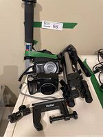 Two Canon digital cameras, Manfrotto monopod stick, Vivitar clamp, and tripod shown together on table.