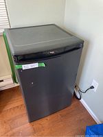 Small black Danby refrigerator with closed door, showing compact size and black finish.