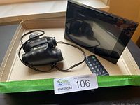 Photo showing Nikon Travelite III binoculars and Sony digital picture frame with remote control placed together in a box.