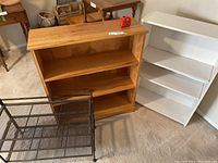 Photo of two wooden shelves and a black metal shoe rack on carpeted floor.