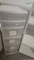 Plastic storage shelf with six sliding translucent drawers, showing drawers partially open to display storage bins.