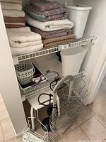 Photo of towels stacked on wire shelves with bathroom racks and bins underneath