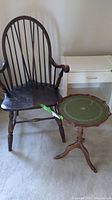 Windsor chair with curved back and multiple spindles next to the round green-topped side table and a white desk in background.