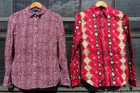 Front view of both button down shirts hanging, showing patterns and button closures
