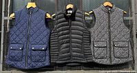 Three women's size small puffer vests on hangers, showing navy blue polka dot Catherine Malandrino vest, black 32 Degrees vest, and black and white houndstooth Malandrino vest.