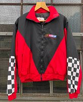 Front view of vintage 1997 NASCAR jacket showing red and black color blocking, checkered flag sleeves, and front embroidered NASCAR logo