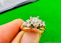 Ring held between fingers showing front profile and prong setting