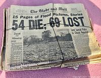 Bundled newspapers with large flood disaster headline from The Globe and Mail dated Sunday, May 1, 1951, showing 54 dead and 69 lost in flood.