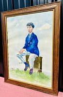 Full view of the framed watercolour portrait of a young boy sitting on a tree stump, wearing a blue blazer and white pants, signed Vernon Mould.