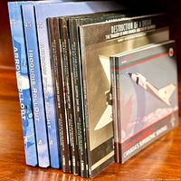 Books standing on a wooden surface showing titles Arrow Rollout, Iroquois Rollout, Arrow First Flight, and multiple copies of The Destruction of a Dream series.