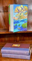 Photo displaying spine and cover condition of all three hardcover books and slip cover with colorful artwork.