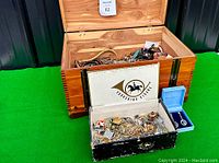 Wide shot showing wooden boxes filled with assorted estate jewelry including brooches, necklaces, and rings.