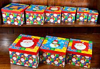 Nine nesting Christmas gift boxes with Santa themed lids and holiday patterns shown arranged to display tops and sides.