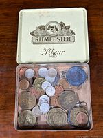 Open Ritmeester Pikeur Mild cigarette tin with assorted vintage coins inside including silver and world coins.
