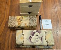 Shows three Victorian celluloid vanity and glove boxes with a Sharpie and auction lot tag for scale.