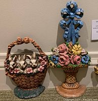 Full view of two cast iron door stops side by side, showing flower basket and bunny basket designs