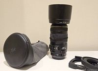 Lens body upright with ET-65 hood attached, pouch and collar on side