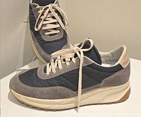 Side angle view showing grey suede and nylon materials, cream laces, and the sole construction.