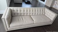 Front view of sofa showing full tufted back, seat cushions and nailhead trim